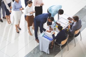 Business people checking in at conference registration table in office lobby