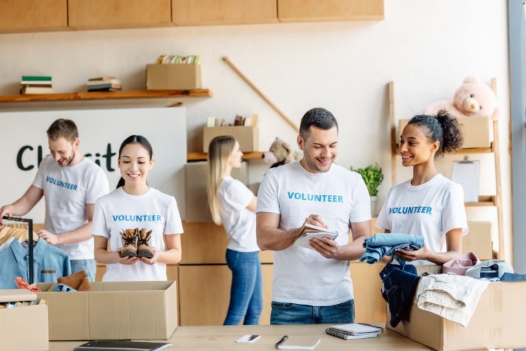 group of young multicultural volunteers in white t-shirts with volunteer inscriptions working in